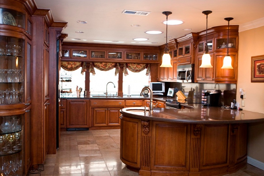 curved cherry cabinets with raised panel doors and fluted columns capped with carved corbels.