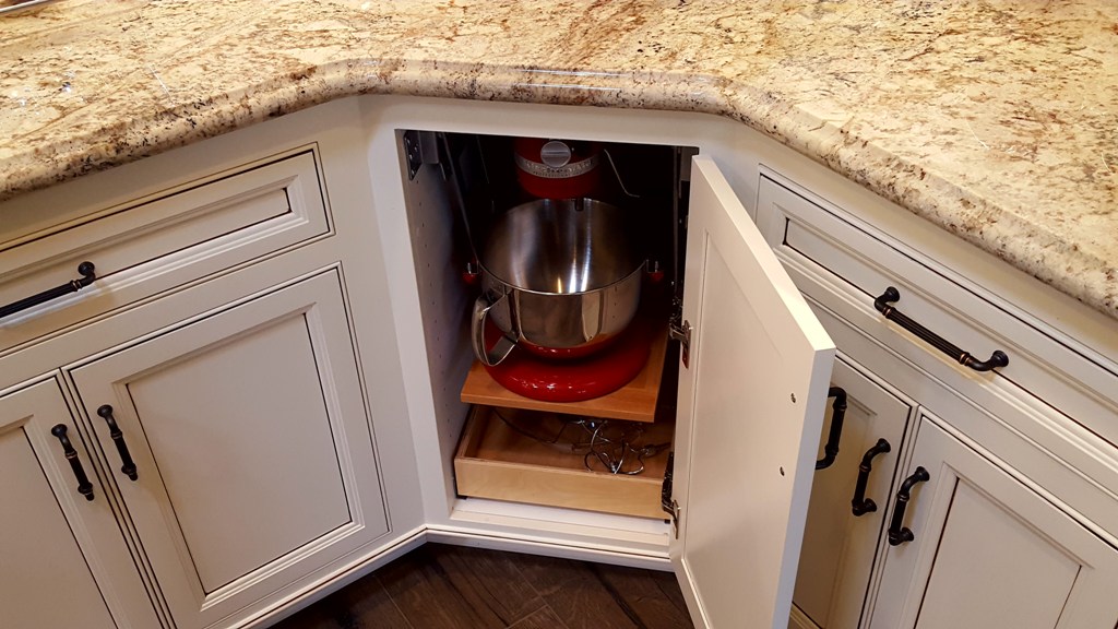 painted and glazed angled corner cabinet door opens to reveal baking center with mixer popup.