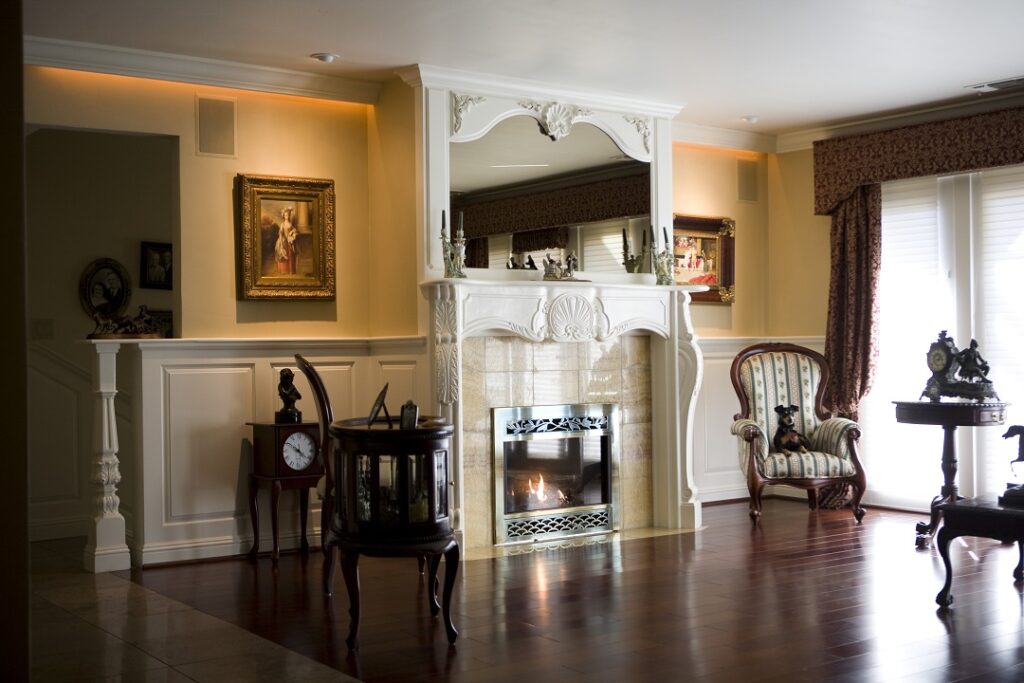 custom carved fireplace mantle flanked by wainscot and capped with crown molding